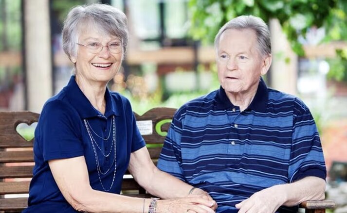 Husband and wife sitting together on a bench outdoors at Traditions at Lakeview Crossing in Groveport, Ohio.